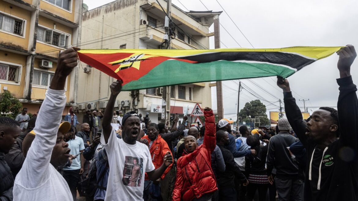 Protesters in Mozambique rally against election results, waving flags and holding signs during a large public demonstration.