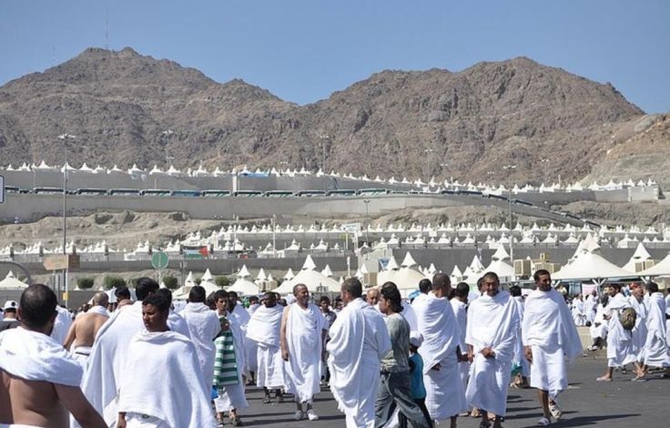 Muslim pilgrims using umbrellas and water bottles to shield themselves from heat in Mecca during Hajj 2025.